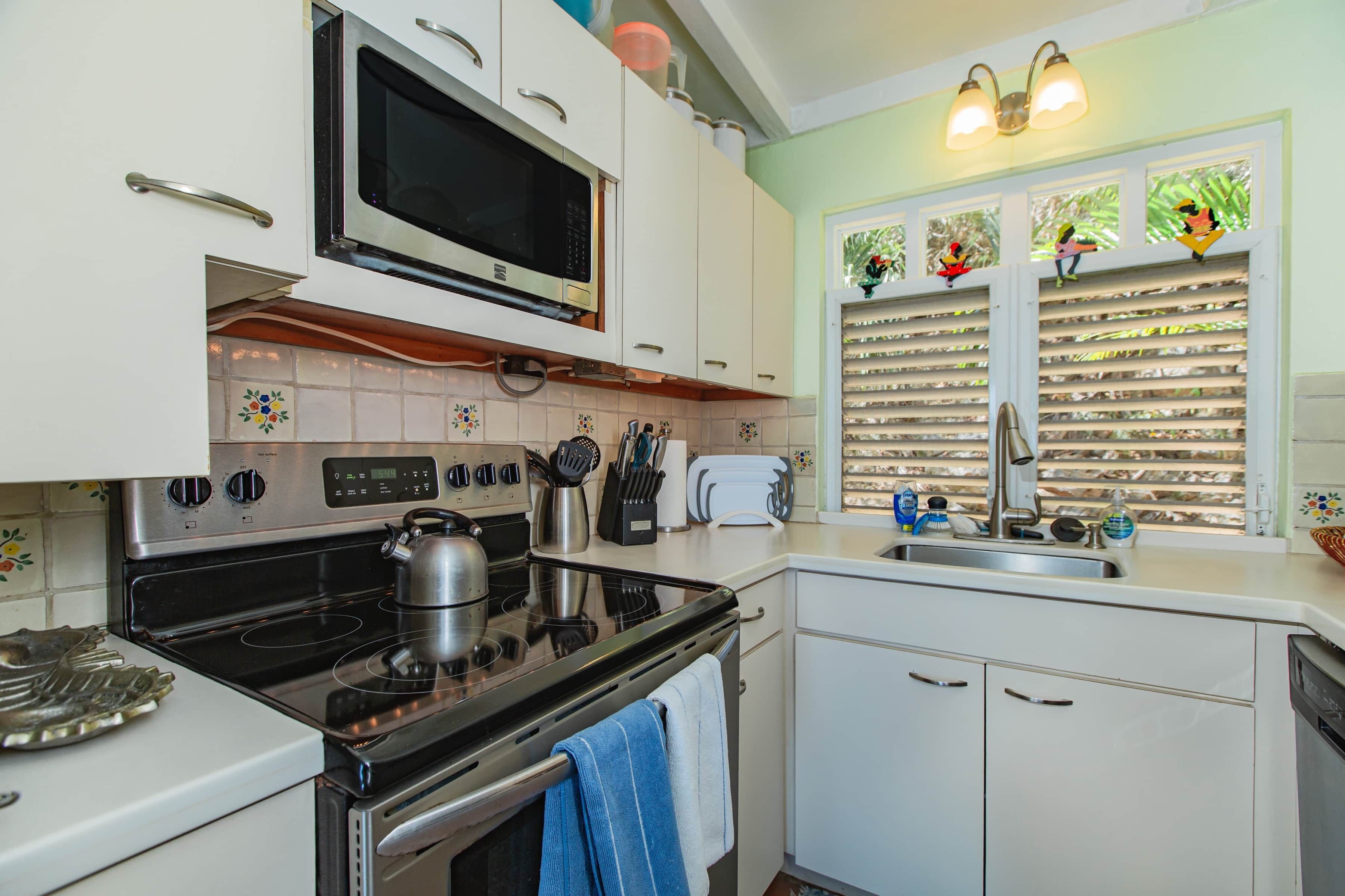 A kitchen with a stove, microwave, toaster, and sink.
