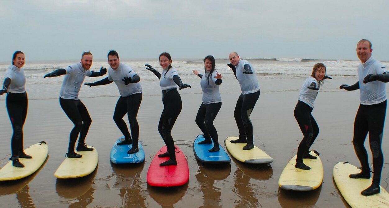 Een groep mensen staat op surfplanken aan het strand.