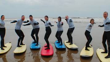 Een groep mensen staat op surfplanken aan het strand.