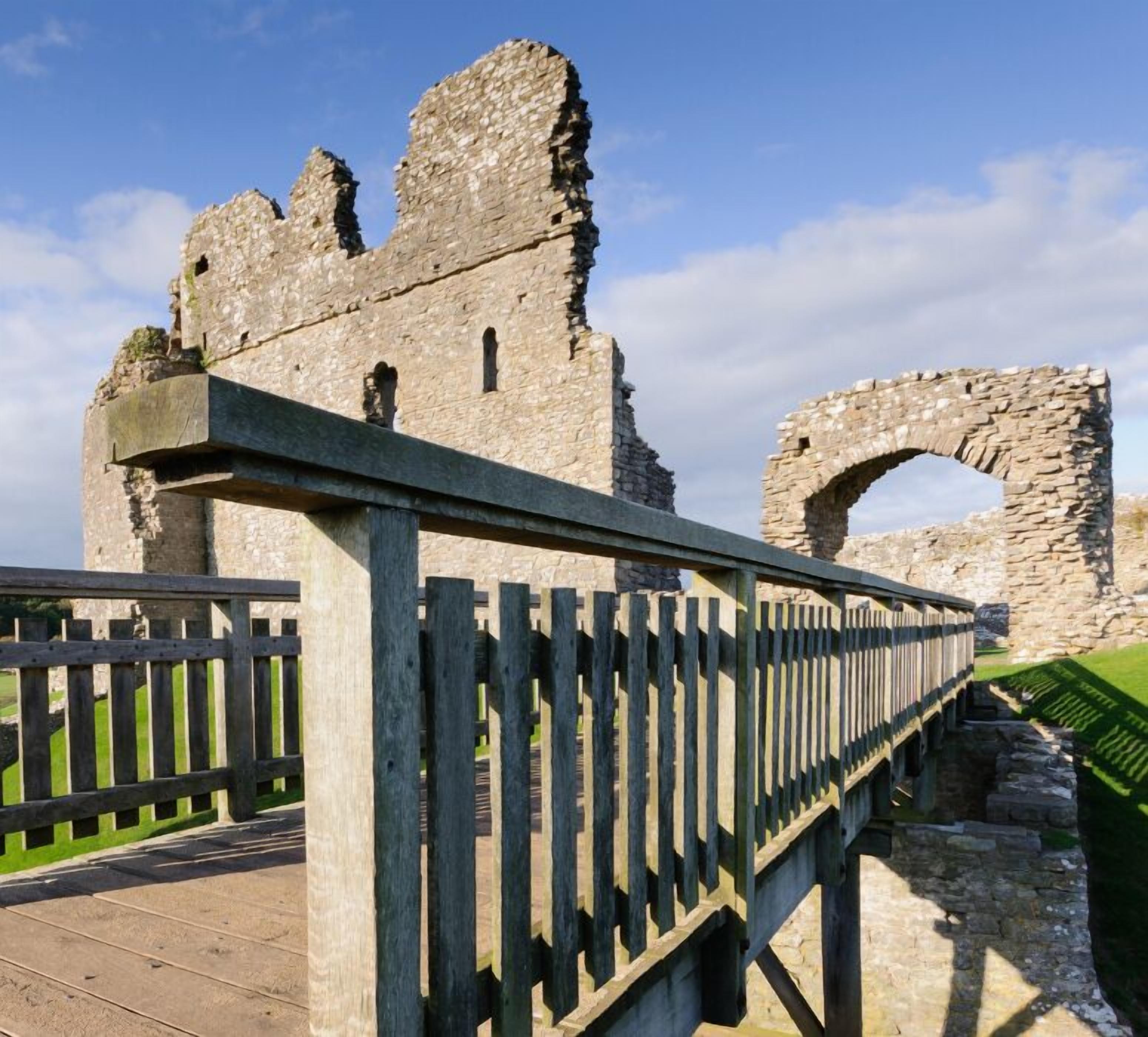 A stone structure with a wooden walkway leading to a large arched opening.