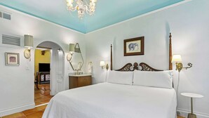 Une chambre à coucher avec un grand lit, un lustre, une table de chevet et un tableau au mur.