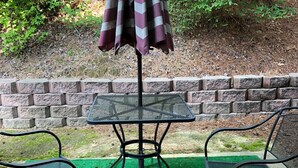 A patio area with a table and two chairs, an umbrella, and a brick wall in the background. - Gated Condo Community and Personal parking, Near campus, WIFI, Washer/Dryer  (Oxford)