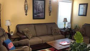 A living room with a brown sofa, a coffee table, a red and beige rug, and a potted plant. - Gated Condo Community and Personal parking, Near campus, WIFI, Washer/Dryer  (Oxford)