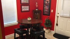 A dining area with a round table, four chairs, a small potted plant, and a cabinet with wine glasses. - Gated Condo Community and Personal parking, Near campus, WIFI, Washer/Dryer  (Oxford)