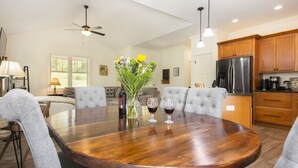 Un comedor amplio con una gran mesa de madera, sillas tapizadas de color gris y un jarrón con flores.