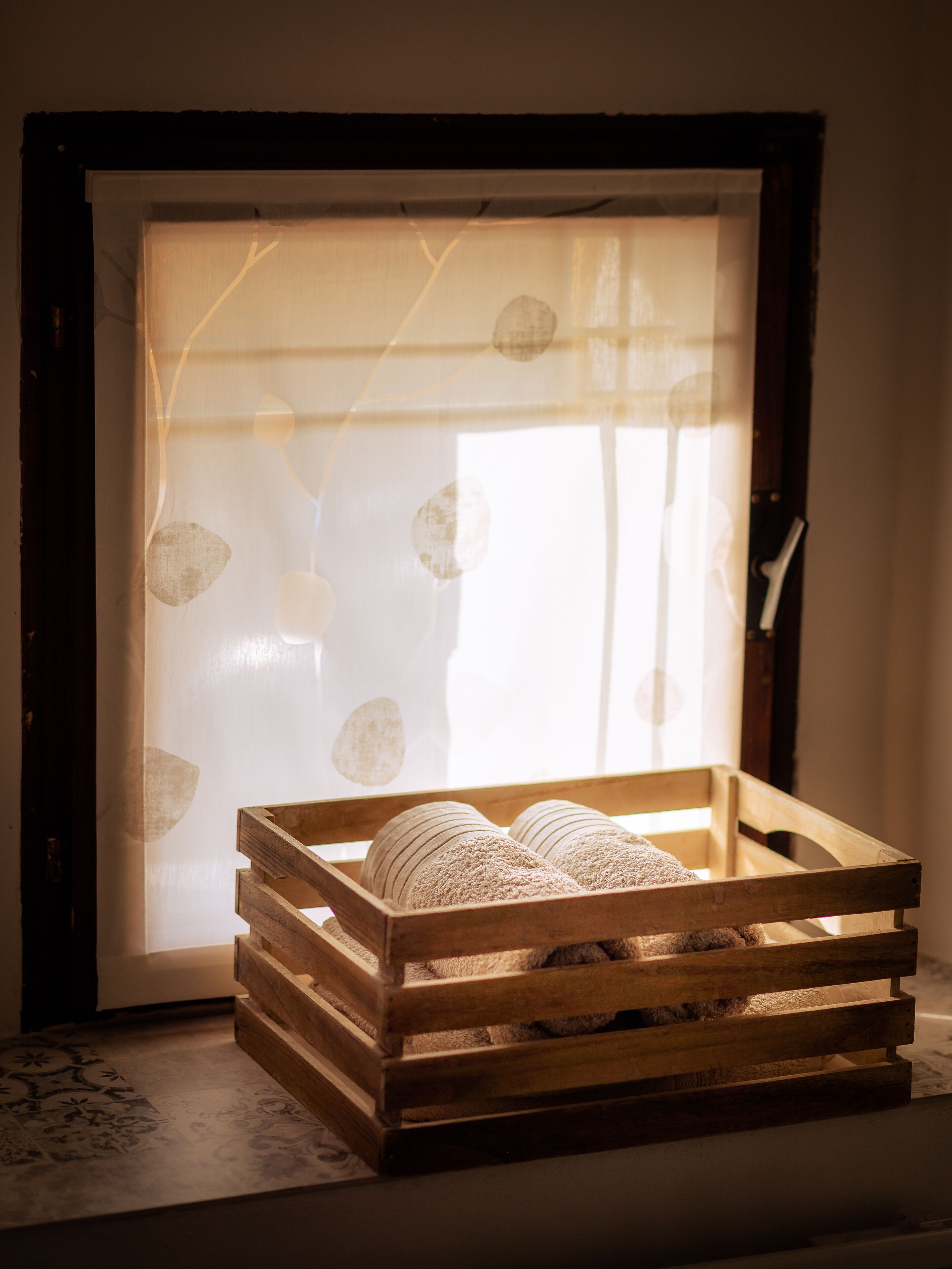 A wooden crate with a woven texture, placed on a patterned rug.