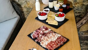 Een houten tafel met een charcuterieplank, kaas en diverse toppings.