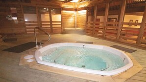 A hot tub in a wooden cabin with a wooden floor and walls, a metal faucet, and a wooden deck surrounding it. - SC105B 1BR/1BA Sleeps six (6) Wi-Fi Parking Near Soaring Eagle Lift and 10 Prime (Snowshoe)