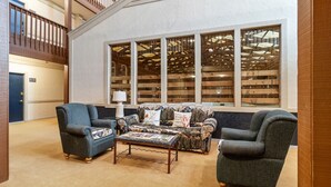 A living room with a sofa, two armchairs, and a coffee table. There is a large window with wooden blinds and a view of a wooden structure outside. - SC105B 1BR/1BA Sleeps six (6) Wi-Fi Parking Near Soaring Eagle Lift and 10 Prime (Snowshoe)