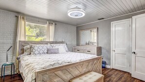 A bedroom with a wooden bed, a bedside table, a bench, a mirror, and a door.