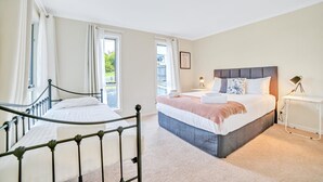 Un dormitorio con una cama grande, una mesita de noche, una lámpara y una ventana con cortinas.