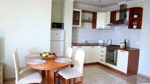 Uma cozinha compacta com área de refeições, equipada com micro-ondas, forno e pia.
