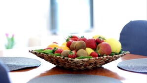 Uma cesta de vime com frutas sobre uma mesa, com um jogo americano.