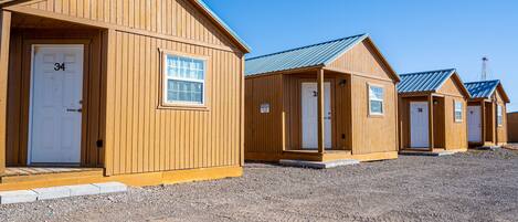 A row of wooden cabins with numbered doors, each with a small window above the door.