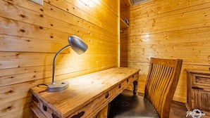 L'intérieur d'une cabane en bois, avec un bureau, une chaise et une lampe.