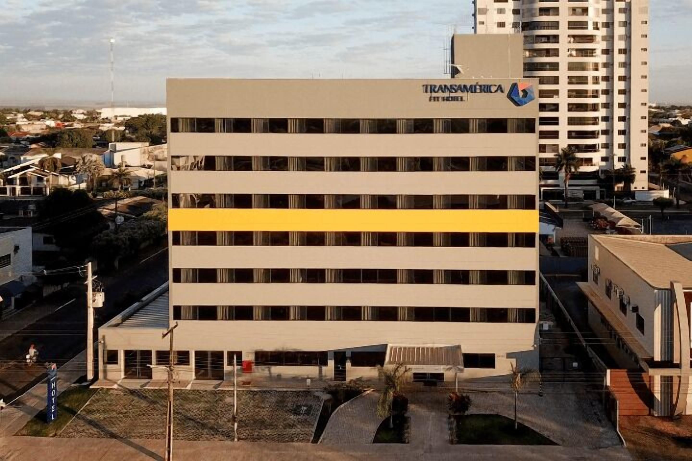 Un edificio de varios pisos con fachada plana, una llamativa banda amarilla y el nombre 'Transamerica' en la parte superior.