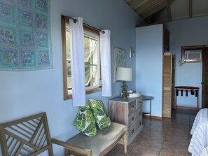 A cozy room with a wooden bench, a dresser, a lamp, and a window with curtains.
