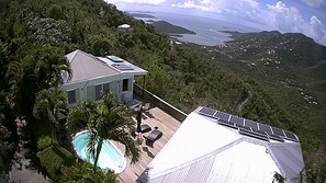 Ein Haus mit Pool, umgeben von üppiger Vegetation und mit Blick auf die Küste.