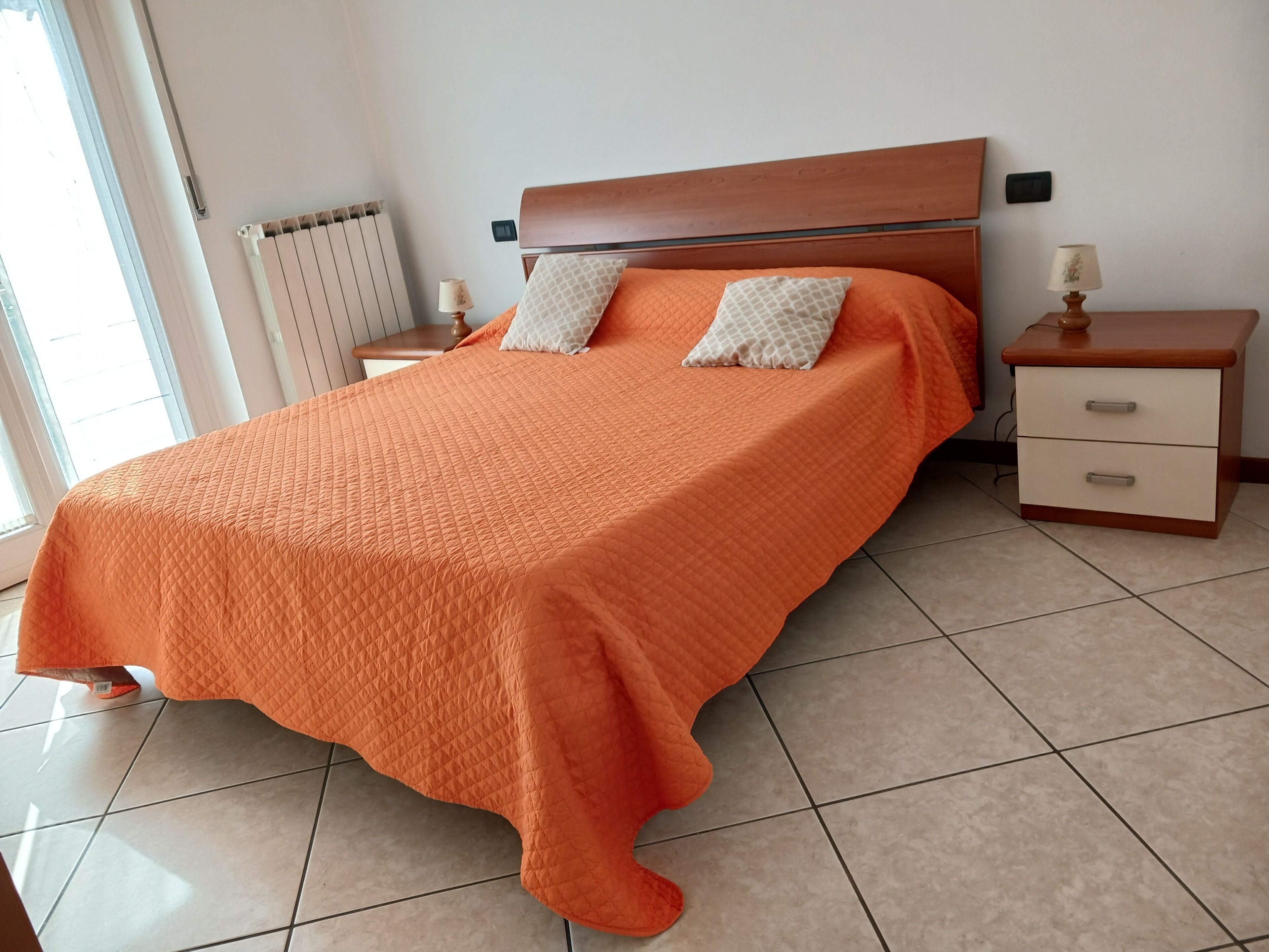 Une chambre à coucher comprenant un lit, des tables de chevet, une commode et un radiateur.