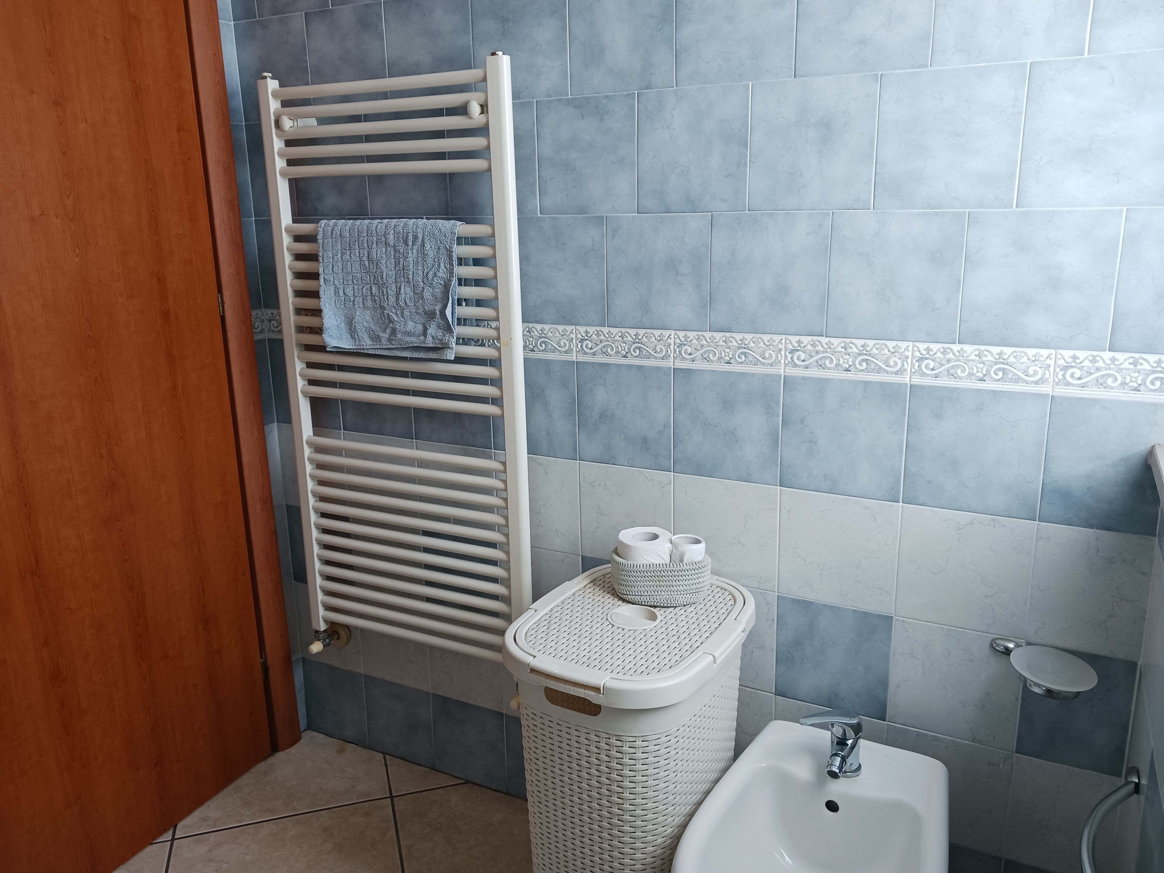 Une salle de bain avec un porte-serviettes blanc, un panier en osier blanc, un lavabo blanc et des toilettes.