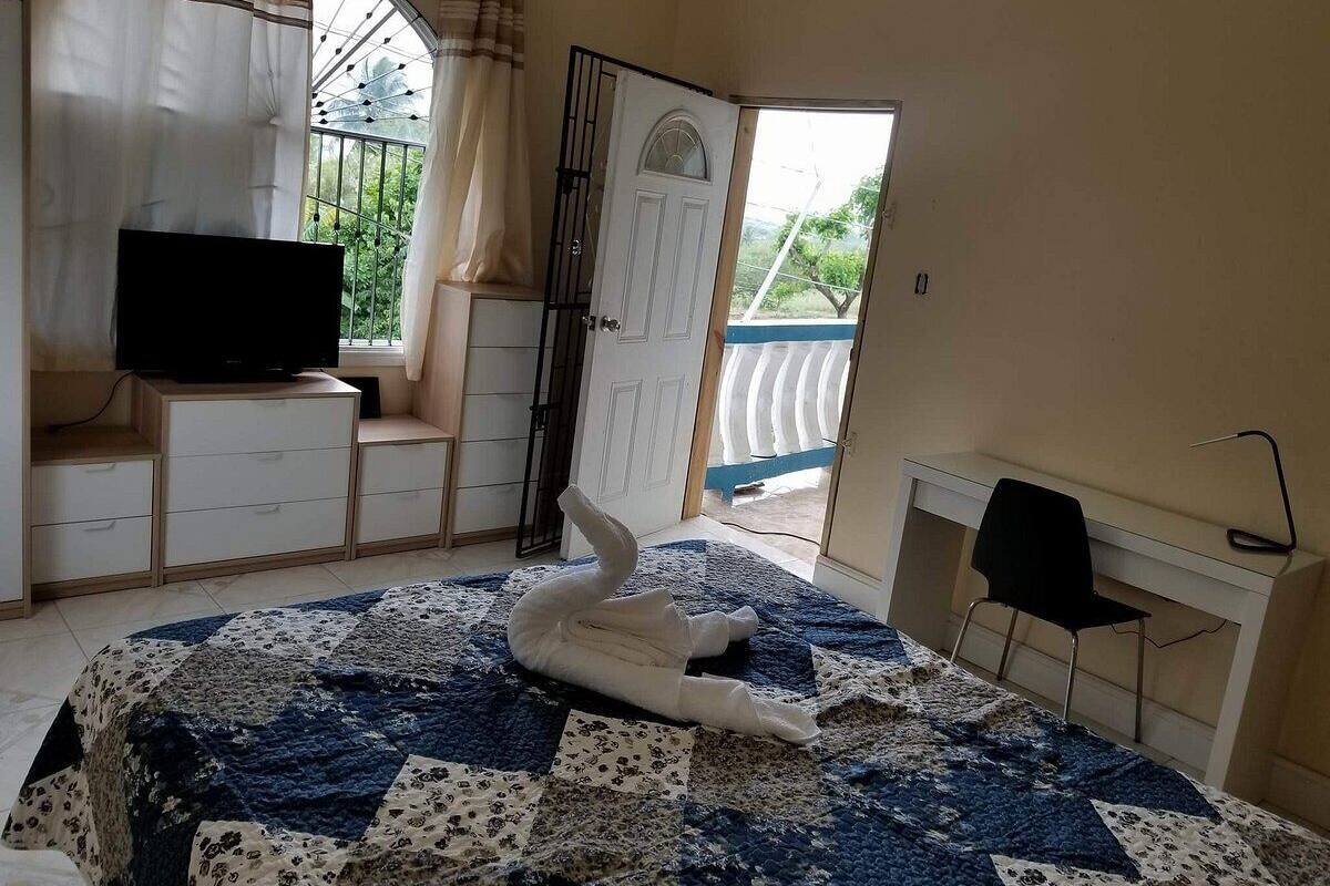 Ein Schlafzimmer mit Bett, Fernseher, Schreibtisch und Stuhl.