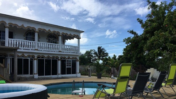 Une piscine avec des chaises longues, un jacuzzi et un bâtiment à deux étages doté de balcons.