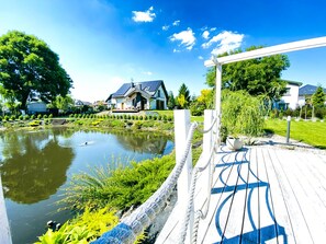 Un quartier résidentiel doté d’un étang, d’une terrasse en bois et de maisons équipées de panneaux solaires.