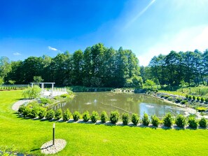 Un jardin bien entretenu, agrémenté d’un bassin, entouré de haies soigneusement taillées et d’une variété d’arbres.