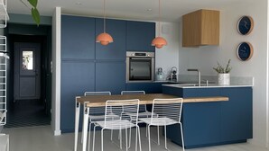 Una cucina moderna con mobili blu, un'isola in legno e sedie bianche.
