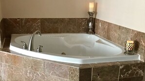Ein Badezimmer mit einer freistehenden Badewanne, Marmorfliesen und einem dekorativen Kerzenständer.
