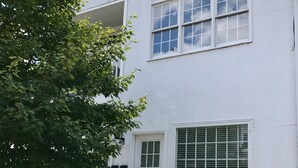 Ein weißes, zweistöckiges Gebäude mit weißem Balkon und einer kleinen Veranda, sowie einer Haier-Klimaanlage.