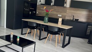 A modern kitchen with black cabinets, a wooden countertop, and a dining area with a black table and chairs.
