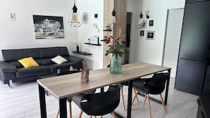 A modern kitchen with a wooden table, black chairs, and a black refrigerator.