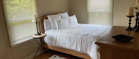A bedroom with a bed, bedside table, lamp, ceiling fan, and a rug.