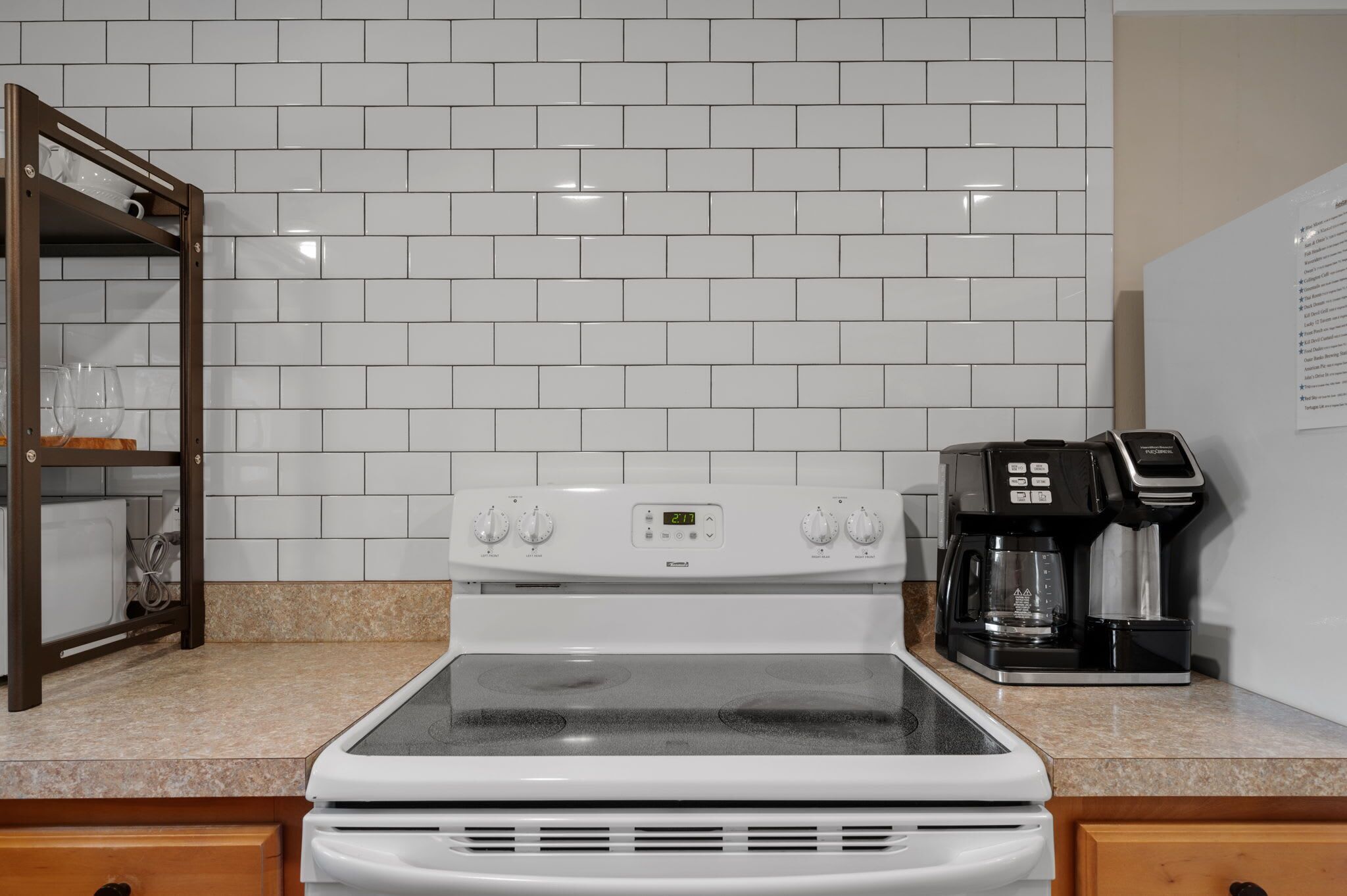 A kitchen with white tiled backsplash, a stove, and a coffee maker.