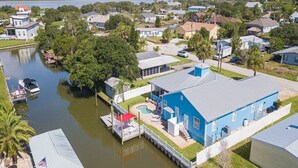 A residential area with a blue house featuring a pool, dock, and a small boat. - Treasure Beach House with private pool and dock (ST. AUGUSTINE)