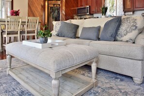 A living room with a sectional sofa, a coffee table, and a dining area with chairs. - Beachfront Villa with Dock & FREE Golf Cart! (Hopkins)