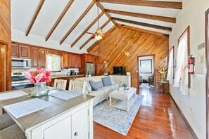 A spacious kitchen with wooden cabinets, a dining area with a table and chairs, a living room with a sofa and a television, and a hallway with a ceiling fan. - Beachfront Villa with Dock & FREE Golf Cart! (Hopkins)