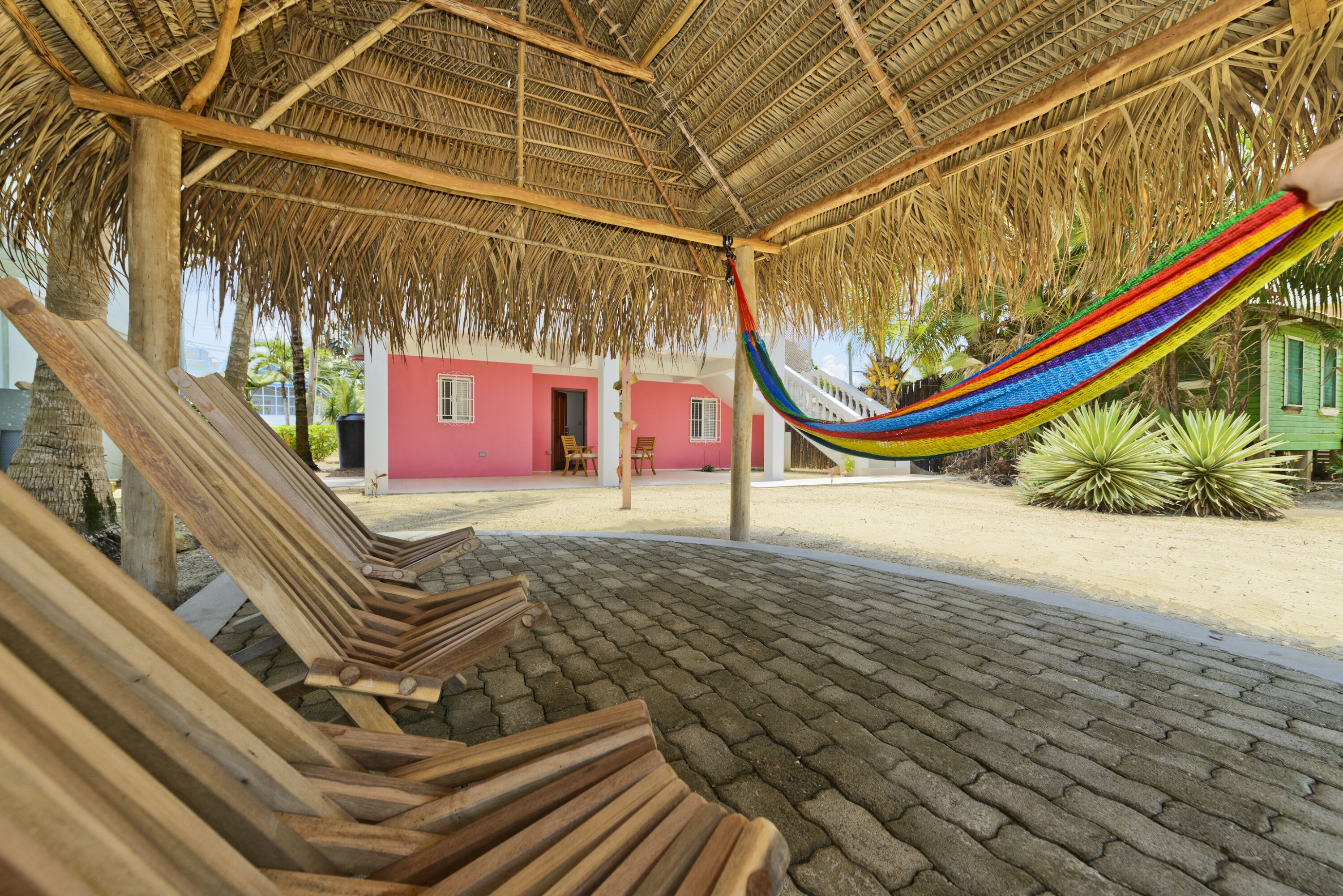 A thatched-roof outdoor area with wooden benches and a hammock.
