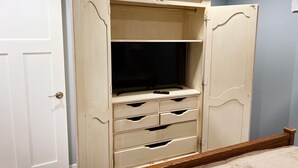 A bedroom with a bed, a wardrobe with multiple drawers, and a door.