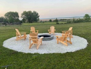 Guests can relax in a tranquil outdoor setting surrounded by a fire pit and Adirondack chairs.