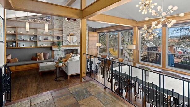 A spacious living area with a fireplace, wooden beams, and a balcony with outdoor seating.
