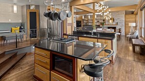 A modern kitchen with a central island, stainless steel appliances, and a dining area with bar stools.