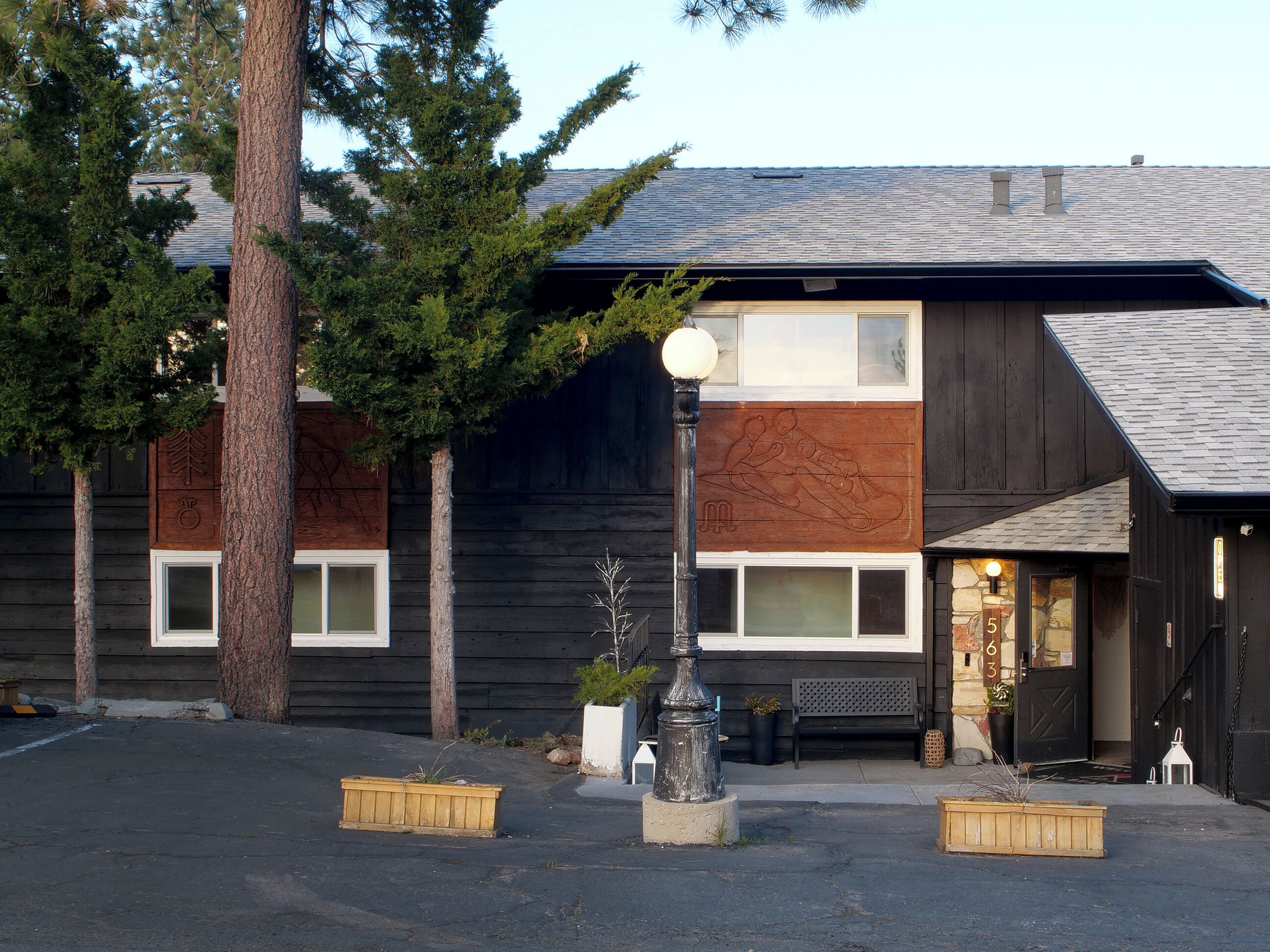 A modern building with a wooden facade, large windows, and a bench outside.