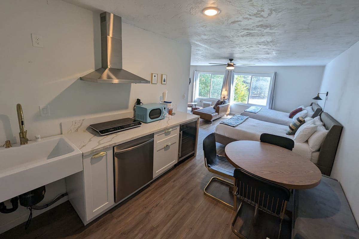 A compact kitchen with modern appliances, a dining area with a round table, and a cozy living space with a sofa and a bed.