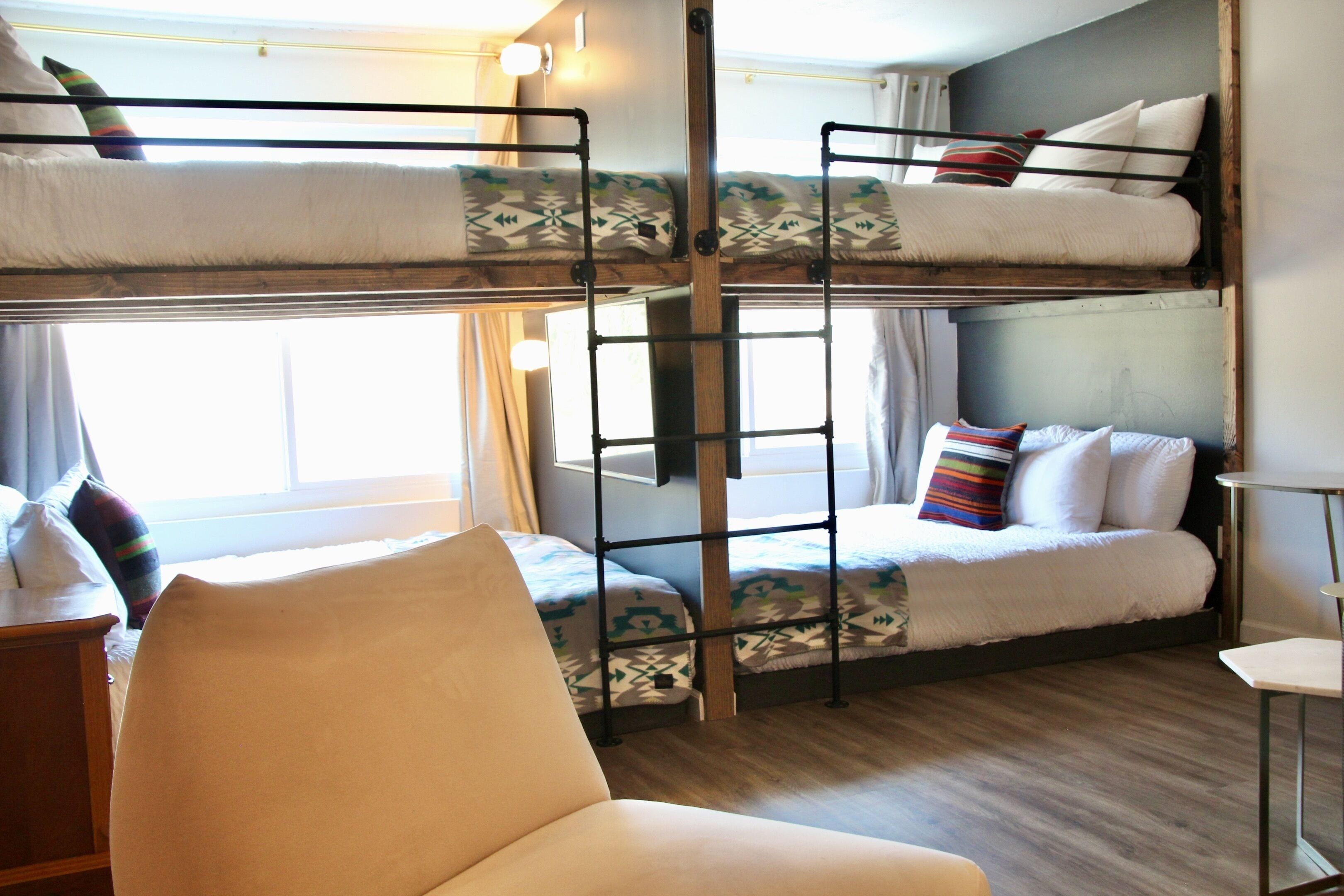 A bunk bed room with a ladder, a chair, and a small table.