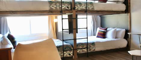 Une chambre avec un lit superposé, une échelle, une chaise et une petite table.