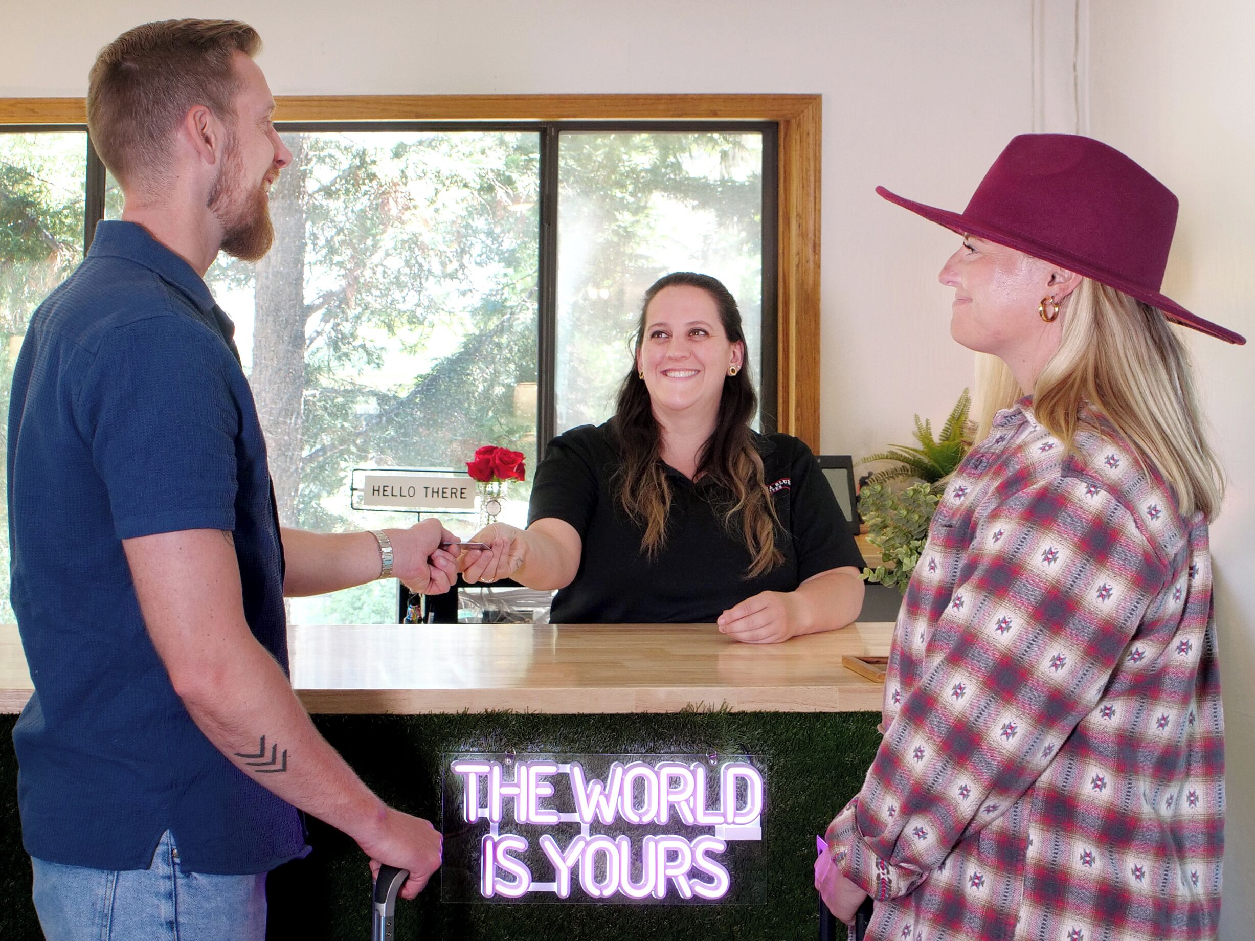 A reception desk with a neon sign that reads "THE WORLD IS YOURS".