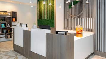 A reception area with a green wall, wooden reception desk, and pendant lighting.