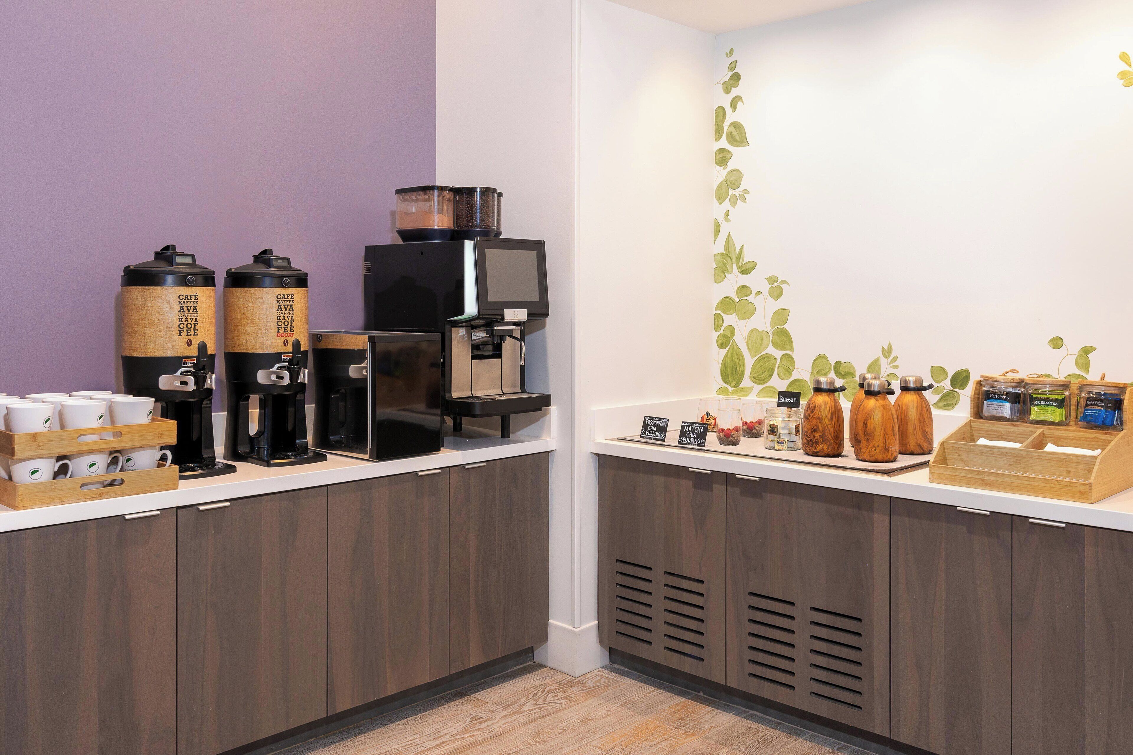 Un espace dédié au café, équipé de plusieurs machines à café, où sont exposés différents types de grains de café, et où un panneau indique la possibilité d’obtenir du café gratuitement.